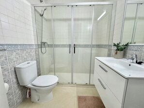 Ein Badezimmer mit Toilette, Duschkabine und Waschbecken inklusive Spiegel.