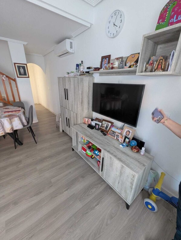 Ein Wohnzimmer mit Fernseher, Holzschränken und einer Wanduhr.