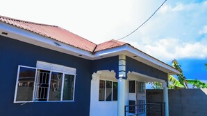 A two-story house with a dark blue exterior, white trim, and a red-tiled roof. - Napper's Secret Peaceful Place (Kampala)