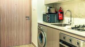 A modern kitchen with stainless steel appliances, a built-in oven, and a washing machine. - Nasma Holiday Homes - Azizi Riviera 46 (Dubai)