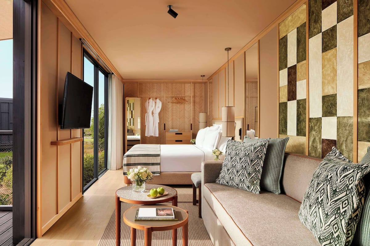 Une chambre d’hôtel moderne dotée d’un grand lit, d’un canapé, d’une télévision et d’un balcon avec vue.
