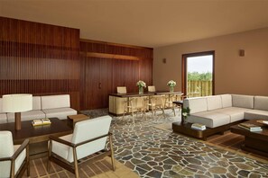 A modern living area with a stone-tiled floor, a wooden panel wall, a sofa set, a coffee table, and a bar area with chairs. - Tivoli Estela Golf & Lodges Porto (Povoa De Varzim)