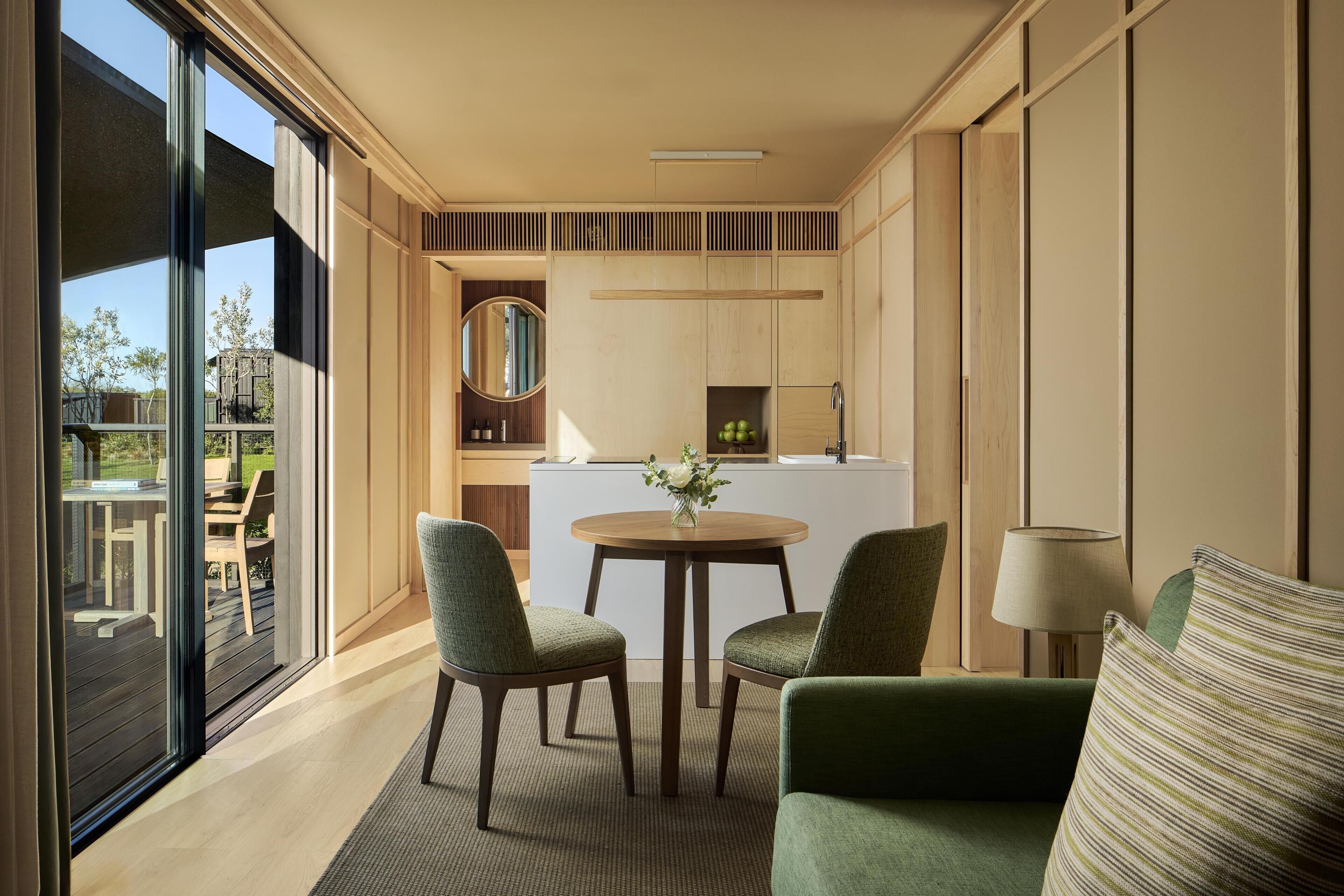A modern interior with a dining area, a kitchen, and a view of the outdoors.