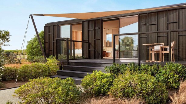 A modern house with a large glass door, a wooden deck, and a dining area with outdoor furniture. - Tivoli Estela Golf & Lodges Porto (Povoa De Varzim)