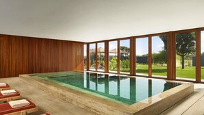 A swimming pool with a view of a garden and a wooden wall. - Tivoli Estela Golf & Lodges Porto (Povoa De Varzim)