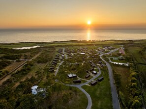 Vista aérea de un complejo turístico costero con varias cabañas, un campo de golf y un puerto deportivo.