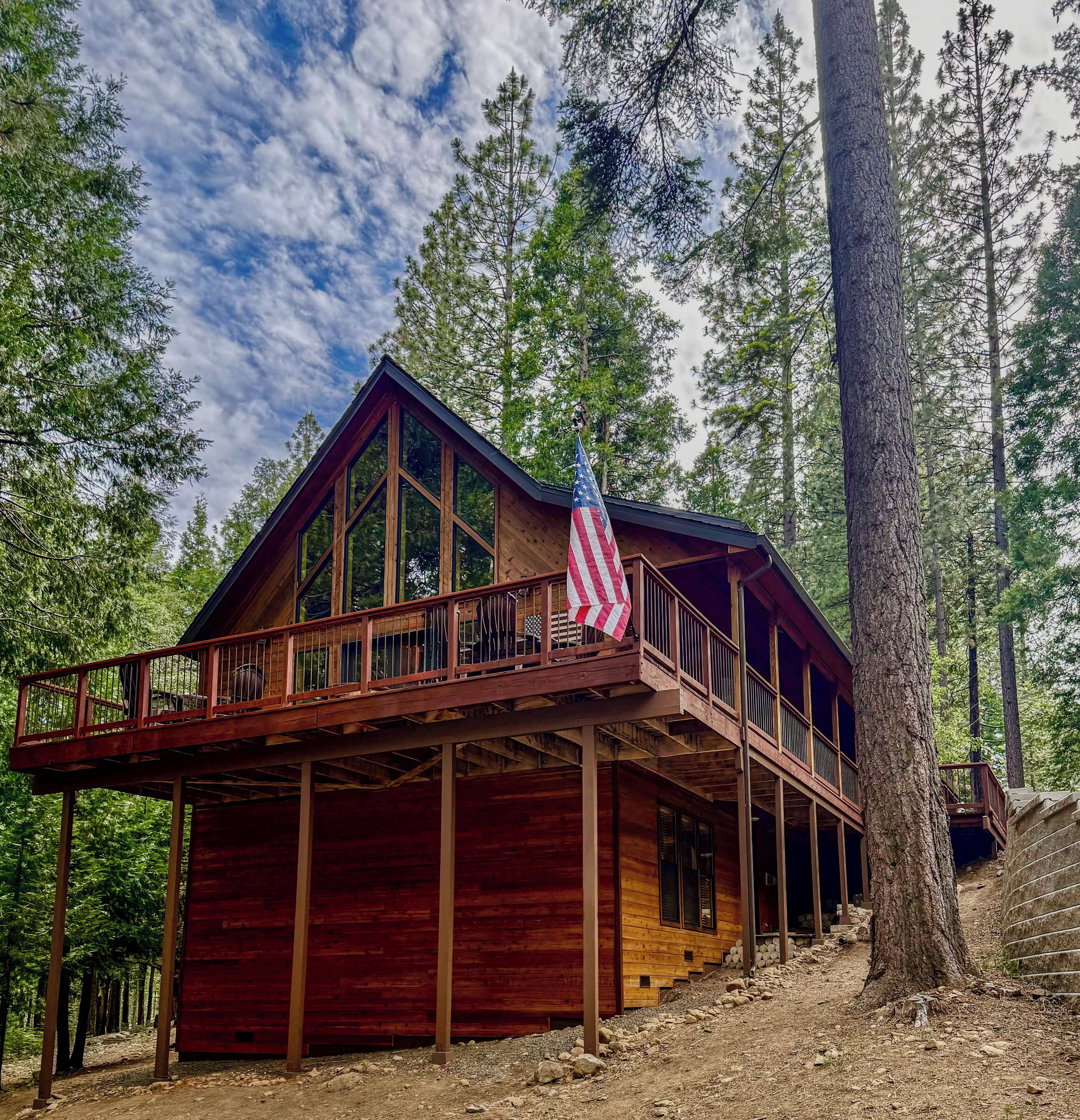A wooden cabin with a balcony, large windows, and an American flag.