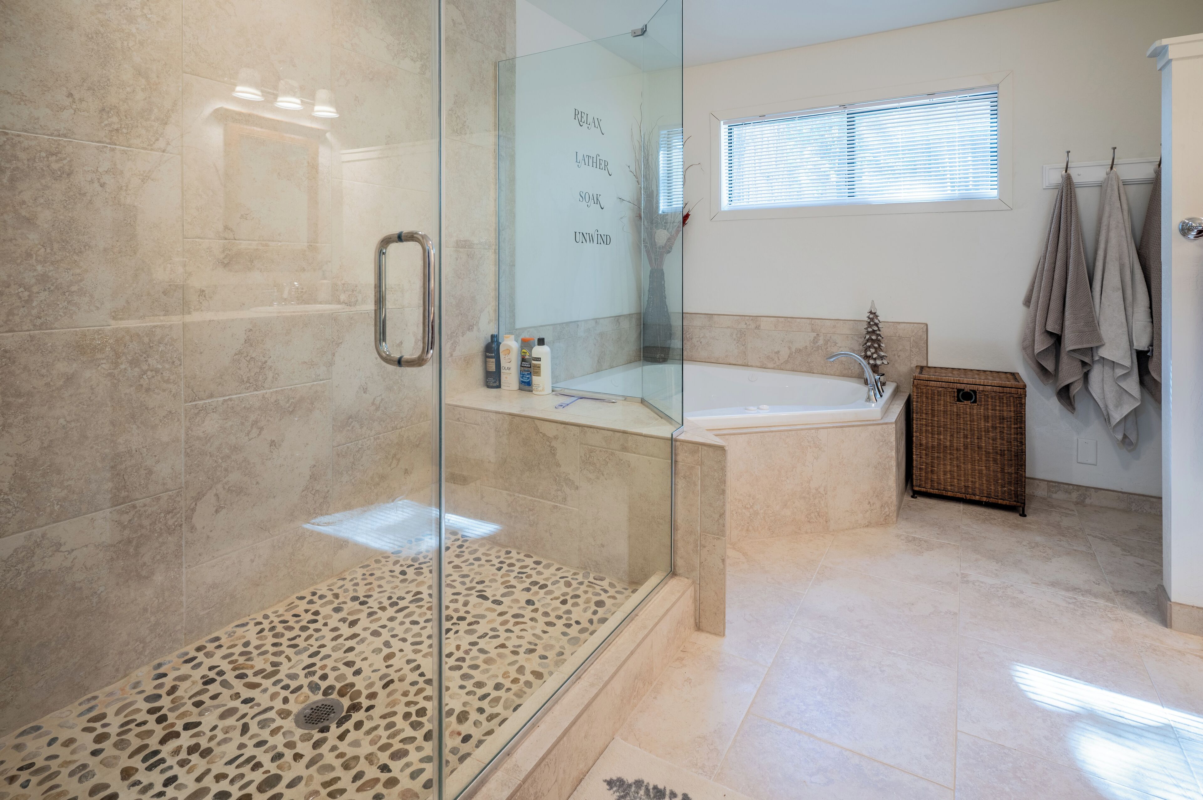 A modern bathroom with a glass-enclosed shower, a freestanding bathtub, and a small window providing natural light.