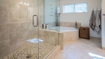 A modern bathroom with a glass-enclosed shower, a freestanding bathtub, and a small window providing natural light.
