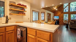 Une cuisine dotée de meubles en bois, d’un lave-vaisselle et d’un coin repas avec une table et des chaises.