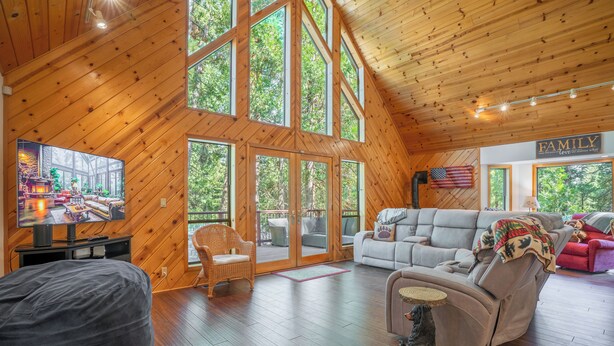 Un intérieur spacieux en bois, doté d’un grand téléviseur, de sièges confortables et offrant une vue sur l’extérieur.