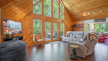 A spacious wooden interior with a large TV, comfortable seating, and a view of the outdoors.