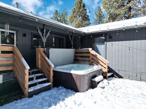 A hot tub in a snowy outdoor area with wooden steps leading up to it.