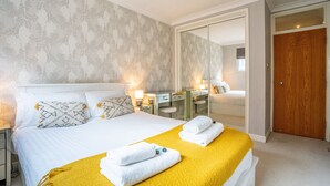 Una habitación de hotel con cama, mesitas de noche, un escritorio y un espejo.