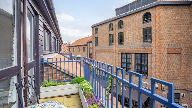 Un patio con barandilla de metal azul, edificios de ladrillo y una escalera.