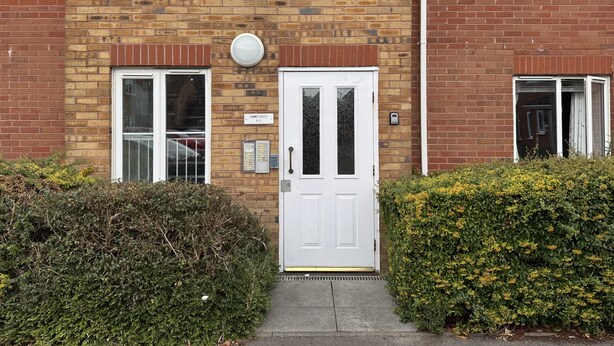 A two-story brick building with a white front door, a small window with a white frame, and a visible doorbell. - Spacious Tidy Room in Cardiff City (Cardiff)