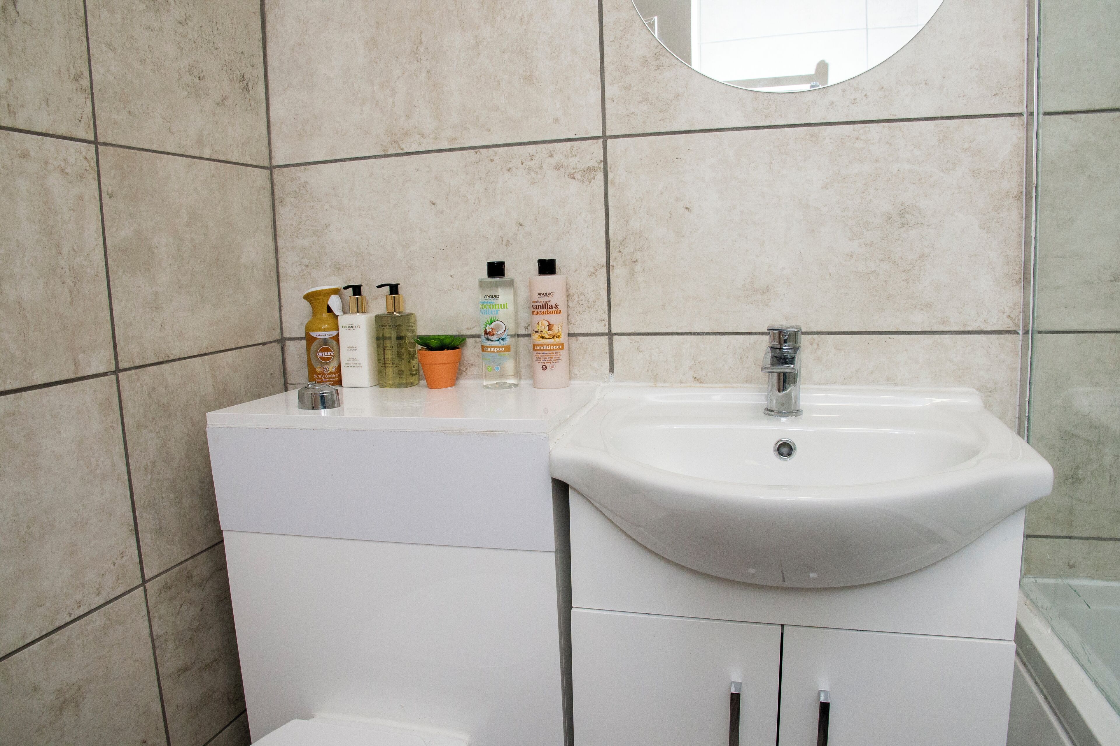 A bathroom with a white sink, a mirror, and toiletries on the counter.