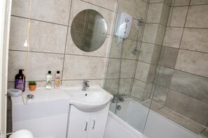 A bathroom with a white sink, mirror, and shower. There are toiletries on the sink. - Corby - Sleeps 5 - Parking - Town Centre (Corby)