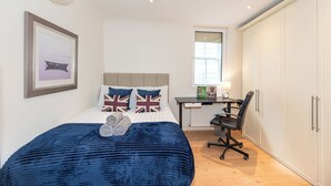 Quarto com cama, escrivaninha e guarda-roupa.