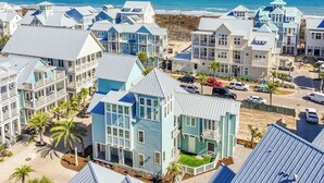A coastal residential area with multiple houses featuring gabled roofs and balconies, situated near the beach with clear blue skies.