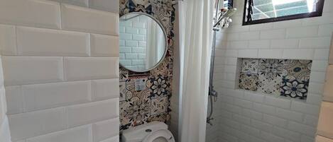A bathroom with a white toilet, a shower with a glass door, and a mirror above the toilet.