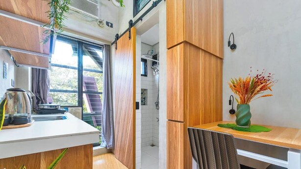 A compact kitchen with a dining area, wooden cabinets, and a view of the outdoors. - Redenza Suites Makati (Makati)