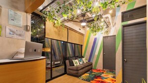 A modern office space with a reception desk, a sofa with cushions, a colorful wall, and a door. - Redenza Suites Makati (Makati)
