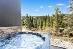 Ein Whirlpool mit Steinwand und Blick auf einen Wald.