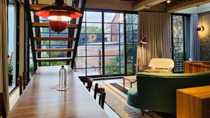 A modern interior with a long wooden table, a green sofa, and a view of the city through large windows. - w Prestigious Duplex w Perfect Deco in Poblado (Medellín)