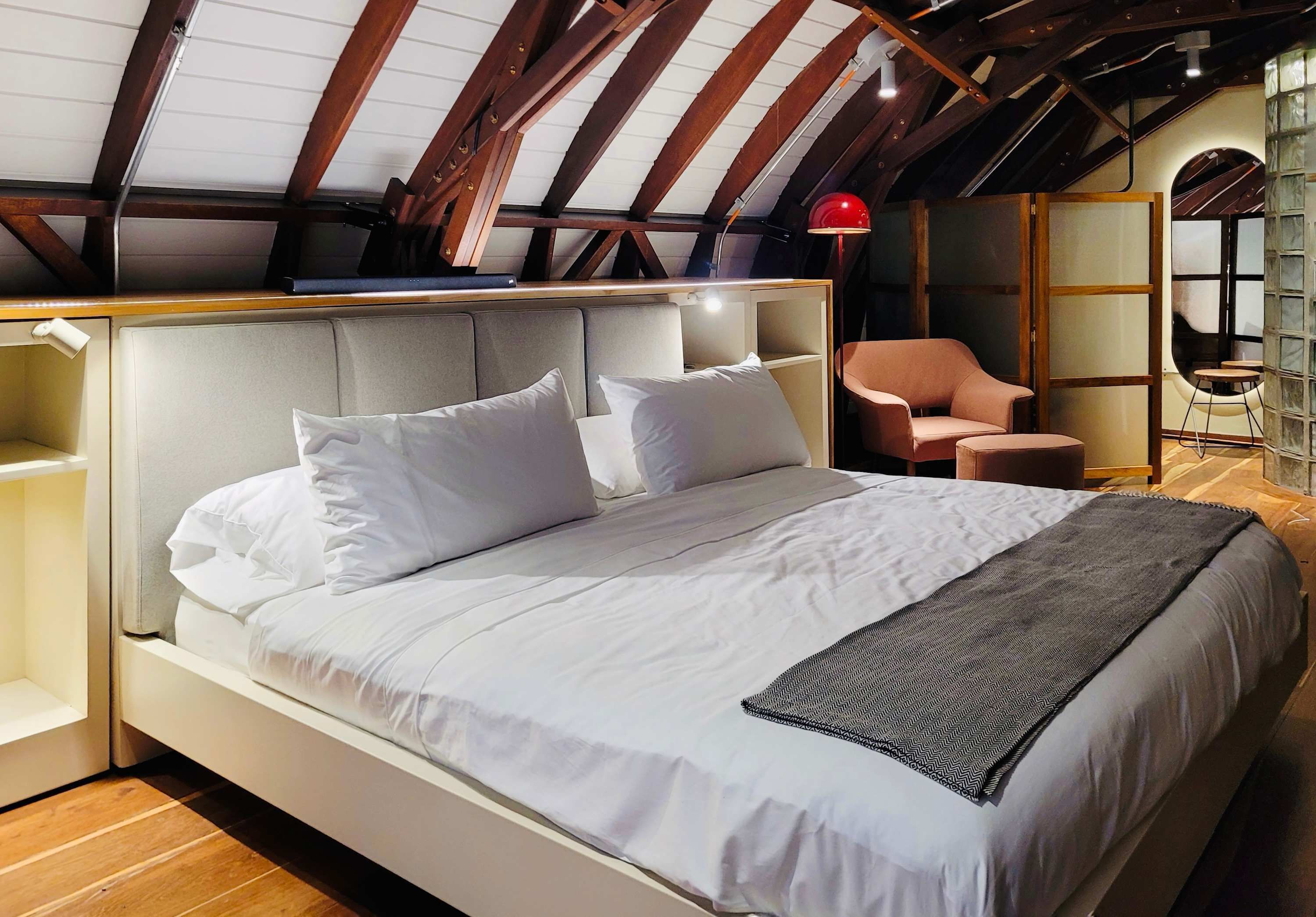Camera da letto moderna con un letto grande, una lampada rossa e un soffitto in legno.
