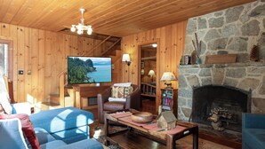 Een gezellig interieur van een blokhut met een stenen open haard, houten wanden, een televisie en een comfortabele zithoek.