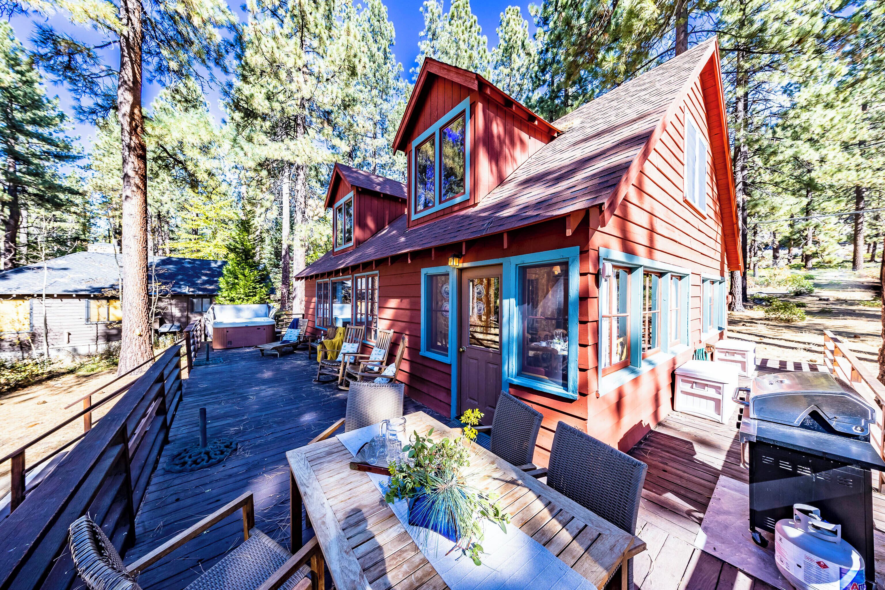 Eine rote Holzhütte mit einer Terrasse, Sitzgelegenheiten im Freien und einem Grill.