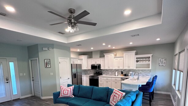 A modern living room with a sectional sofa, a coffee table, and a dining area with a blue chair.