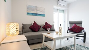 A modern living room with a grey sofa, a white coffee table, a patterned rug, and a lamp.