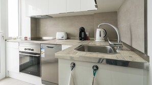 A modern kitchen with white cabinets, a stainless steel sink, a coffee maker, and a toaster.