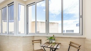 A room with a tiled floor, a wooden table with two chairs, a potted plant, and a bottle of wine. - Urban City View Apartment (Lagos)