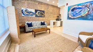 Un salon avec un mur en briques, un canapé, une table basse et un tableau.