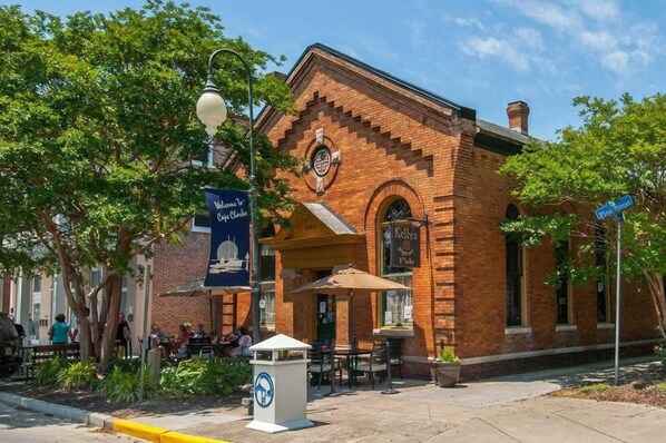 Un edificio de ladrillo con un letrero que dice 'Kelly's Pub' y mesas al aire libre.