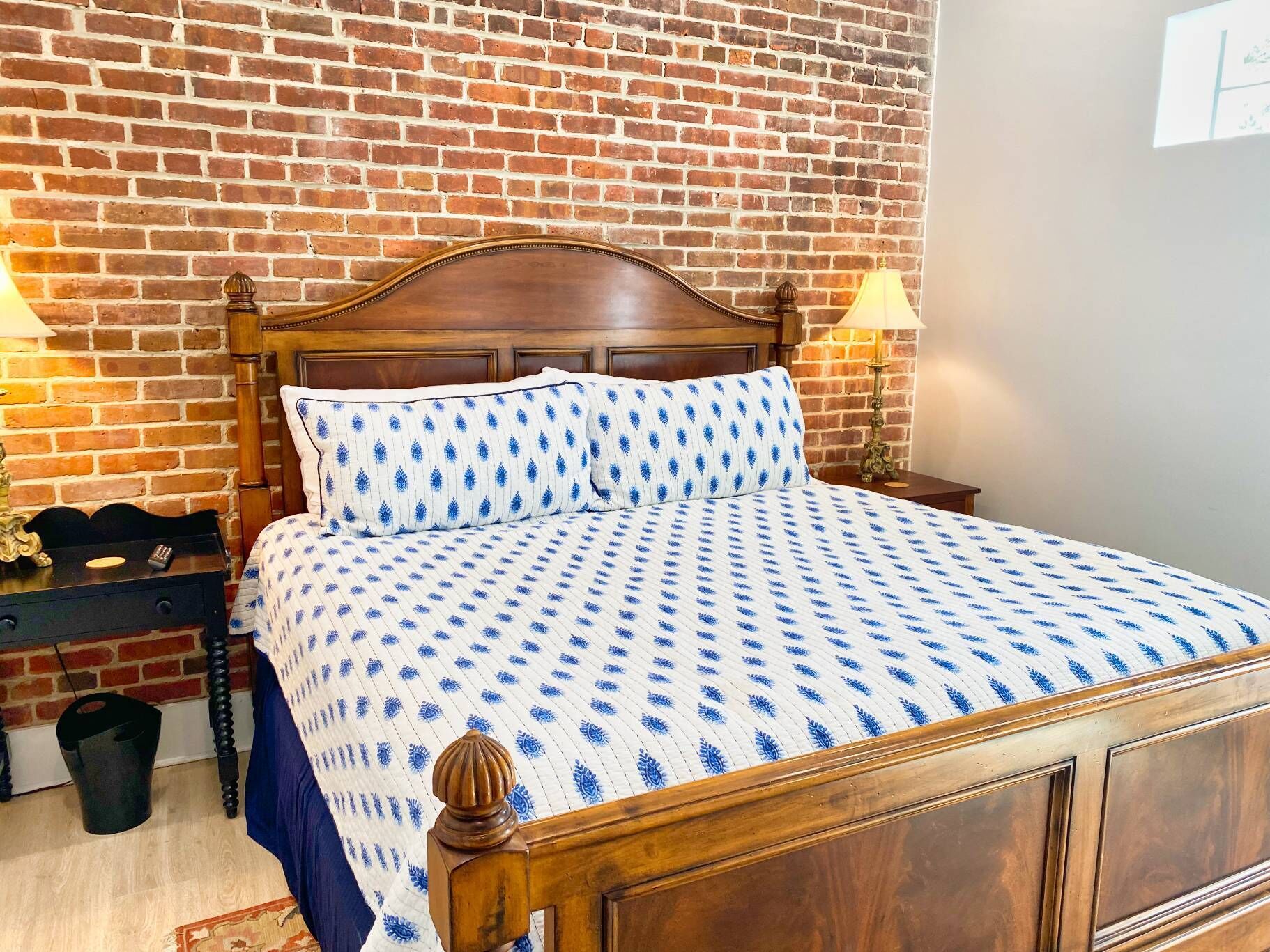 A bed with a wooden headboard, a patterned bedspread, and two bedside lamps.