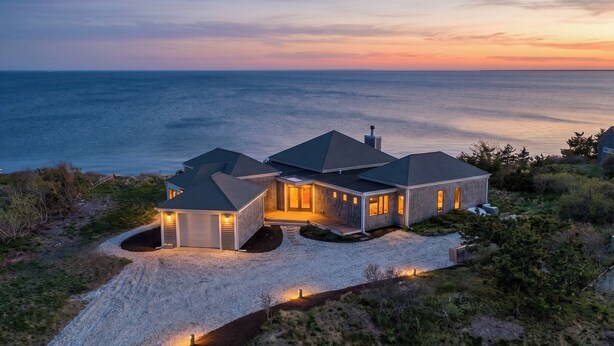 Een huis aan de kust met een grindpad en uitzicht op de oceaan.