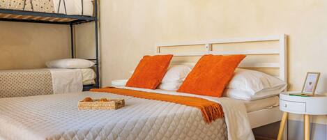 A single bed with an orange throw blanket, a white headboard, and a bedside table with a picture frame.