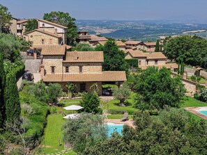 A stone building with a swimming pool, surrounded by lush greenery and a view of the countryside. - SCAPPO IN UMBRIA, la quiete farmhouse (Umbria)