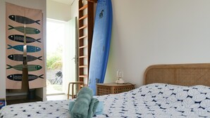 Una camera da letto con un letto, un surf blu, una scala e tende a parete con motivo di pesci.