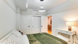 Une chambre à coucher avec un lit, un bureau et une chaise. Les portes sont blanches et il y a une lampe sur le bureau.
