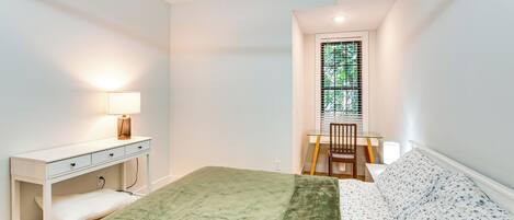 A bedroom with a bed, a desk, and a chair.