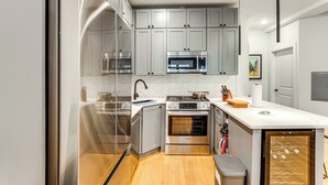 Une cuisine moderne dotée d’appareils électroménagers en acier inoxydable, de meubles de couleur grise et d’un plancher en bois.