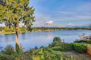 A lake with a tree in the foreground, a dock with a boat, and a distant mountain range.