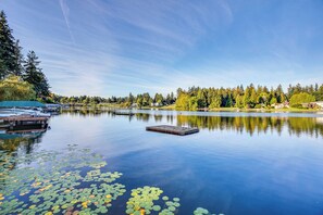 A calm lake with lily pads, docked boats, and a pier.