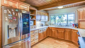 Una cocina con armarios de madera, un refrigerador de acero inoxidable y una ventana con vistas al exterior.
