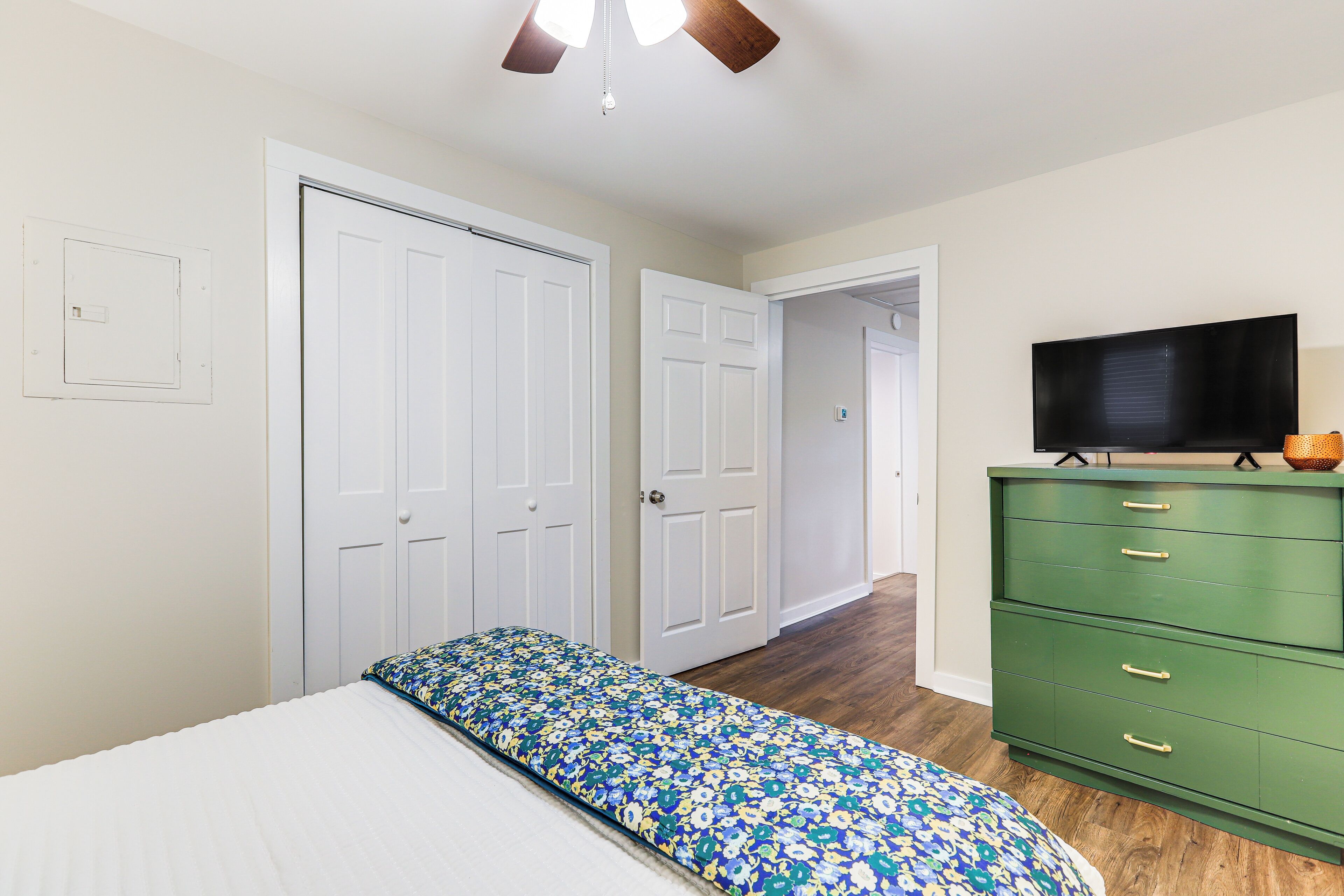 Un dormitorio con una cama, un aparador verde y un televisor.